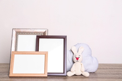 Photo of Photo frames and adorable toys on table against light background, space for text. Child room elements