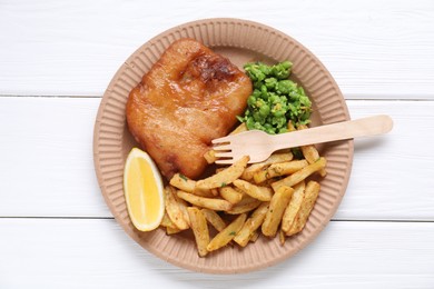 Photo of Tasty fish, chips, peas and lemon on white wooden table, top view