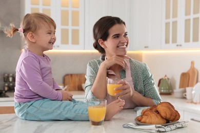 Mother and her little daughter having breakfast together in kitchen