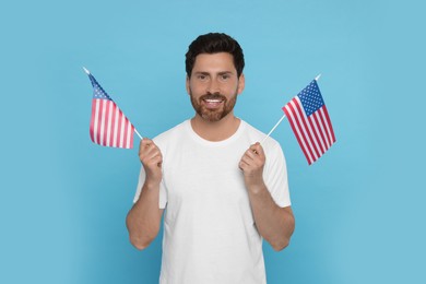 4th of July - Independence Day of USA. Happy man with American flags on light blue background