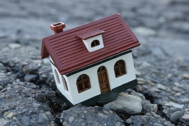 Photo of House model in cracked asphalt, closeup. Earthquake disaster