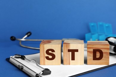 Photo of Abbreviation STD made with wooden cubes on blue background