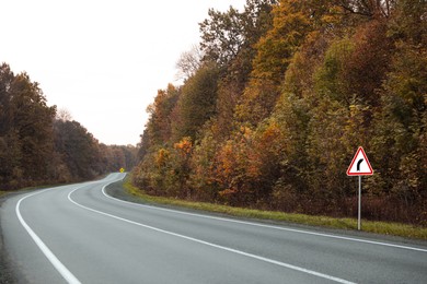 Image of Traffic sign BEND TO RIGHT near empty asphalt road in autumn