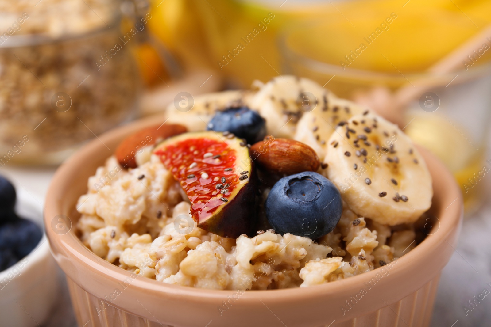 Photo of Bowl of oatmeal with blueberries, almonds, banana and fig pieces, closeup