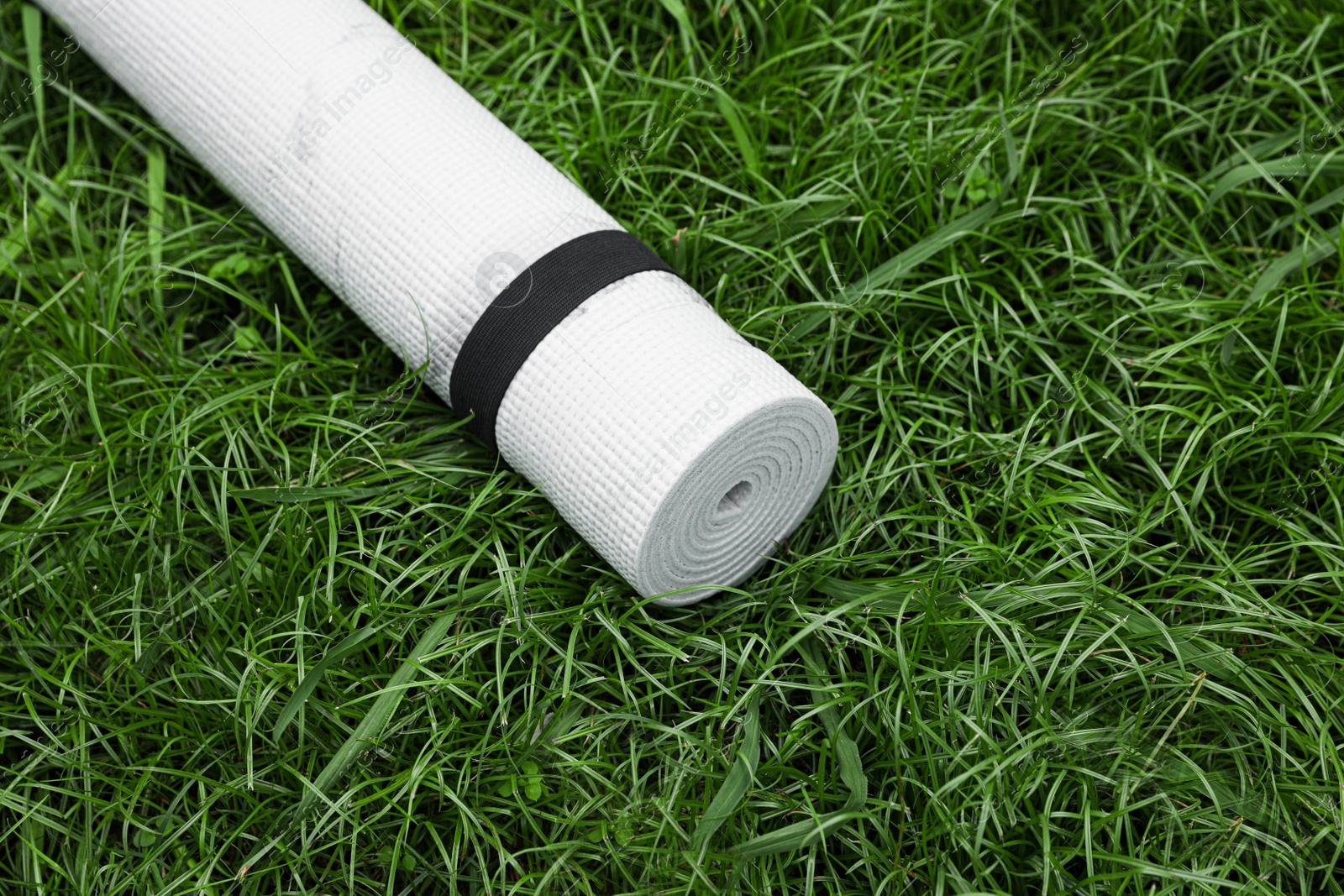 Photo of White karemat or fitness mat on green grass outdoors, above view