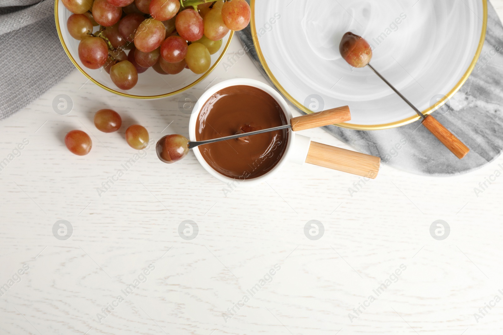 Photo of Flat lay composition with fondue pot and chocolate on white wooden table, space for text