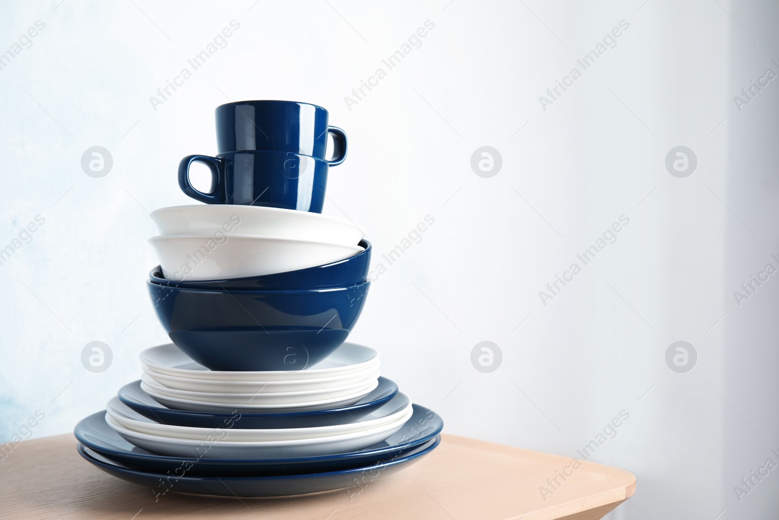 Photo of Set of dinnerware on table against light background with space for text. Interior element