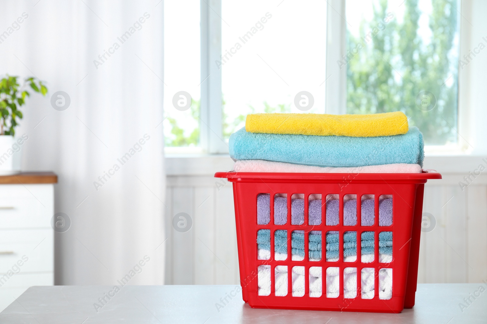 Photo of Basket with clean laundry on table at home, space for text