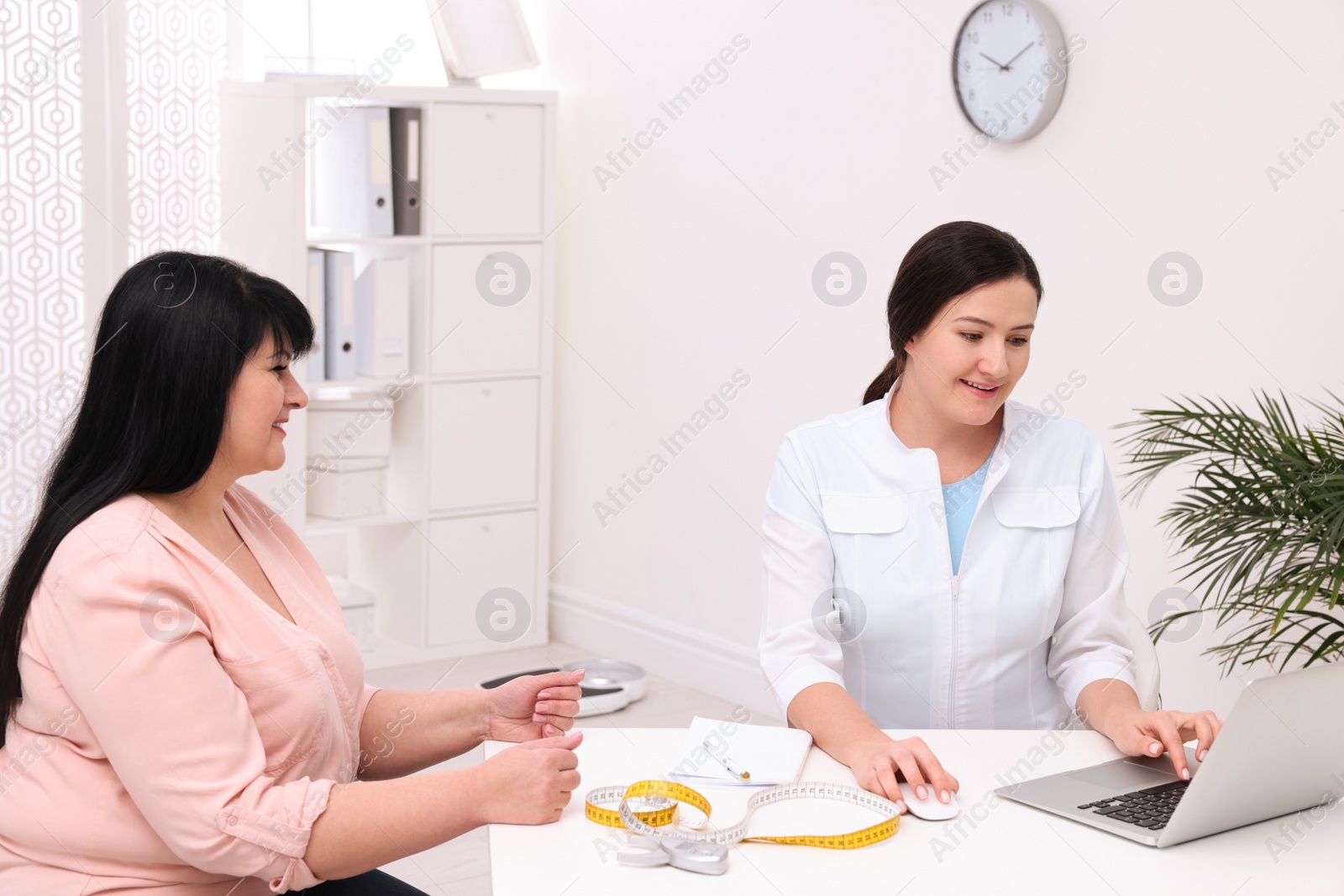 Photo of Overweight mature woman consulting with nutritionist in clinic