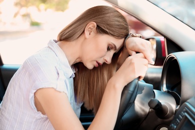 Tired woman sleeping on steering wheel in car