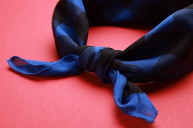Photo of Tied blue bandana with check pattern on red background, closeup