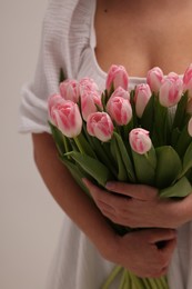 Woman with bouquet of beautiful fresh tulips on light grey background, closeup