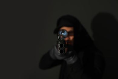 Photo of Professional killer on black background, focus on sniper rifle