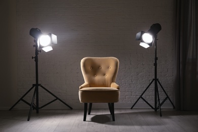 Photo of Interior of modern photo studio with professional lighting equipment and armchair