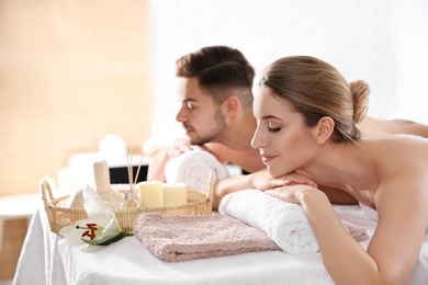 Photo of Young couple with spa essentials in wellness center