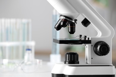 Photo of Modern medical microscope on white table in laboratory, closeup. Space for text