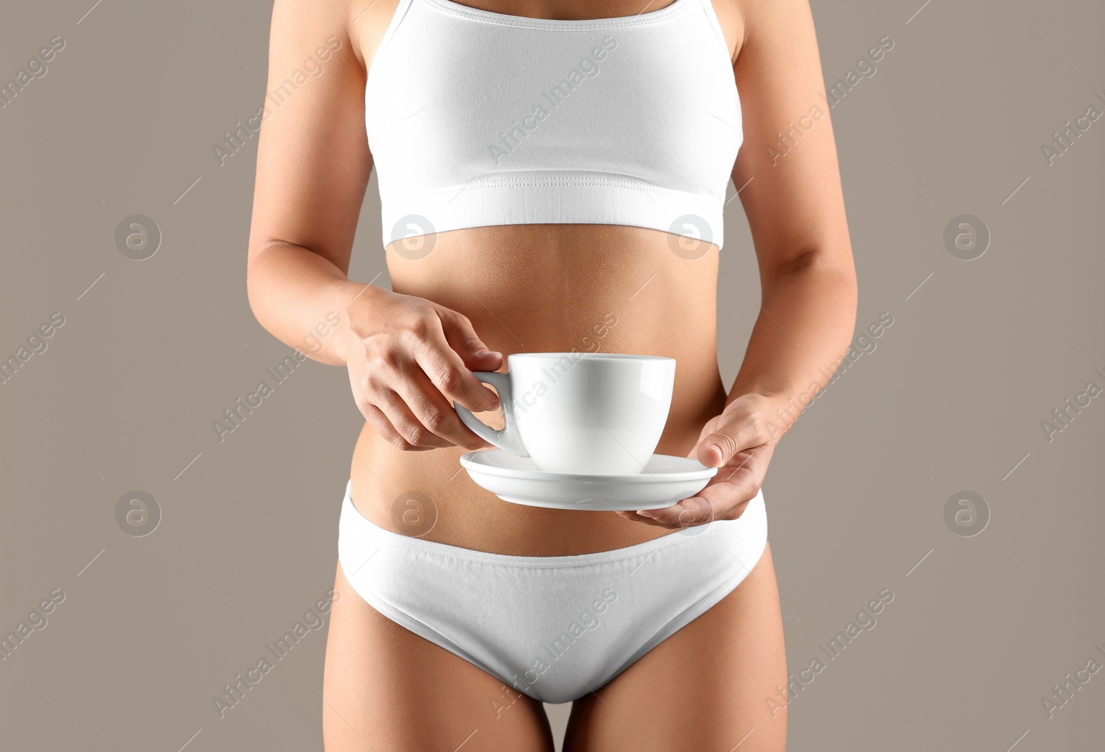 Photo of Young woman holding cup of diet tea on beige background, closeup