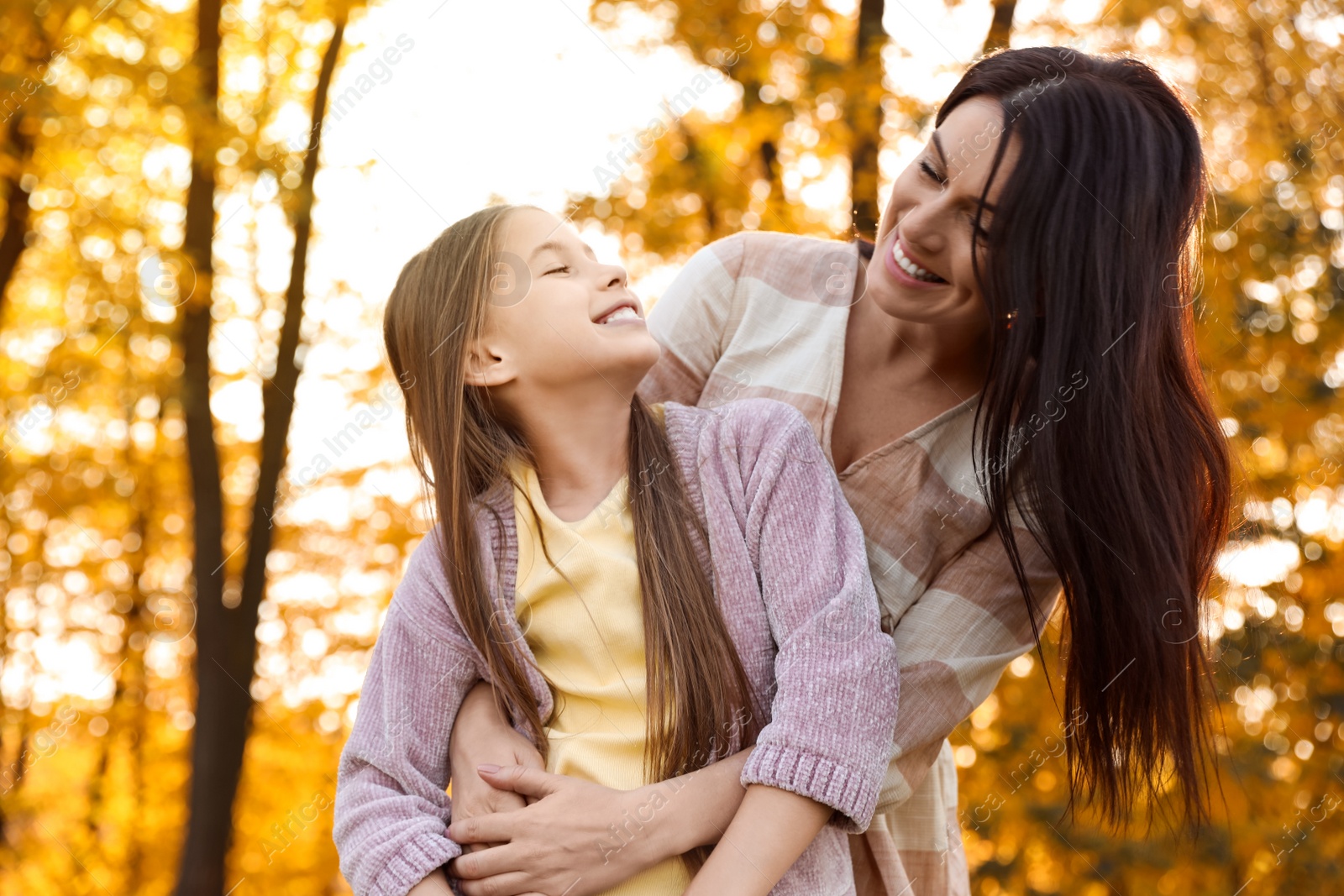 Photo of Happy mother with daughter in sunny park. Autumn walk