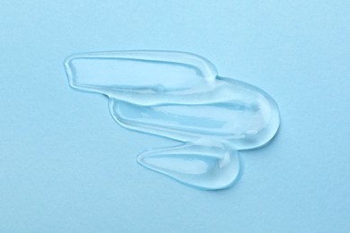 Photo of Swatches of cosmetic gel on light blue background, top view
