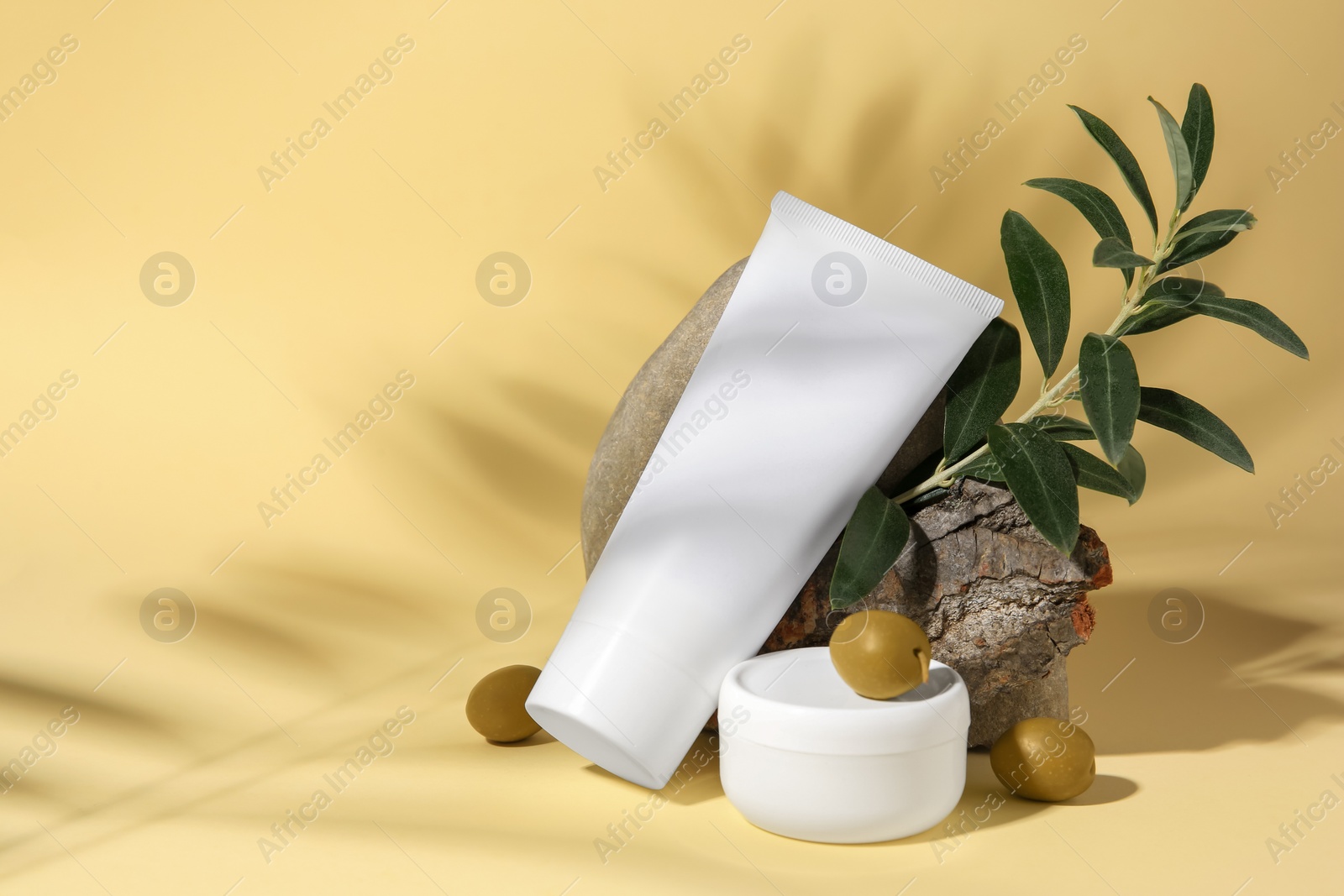 Photo of Cosmetic products and olives on beige background, space for text