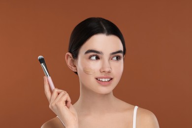 Teenage girl with swatch of foundation and makeup brush on brown background