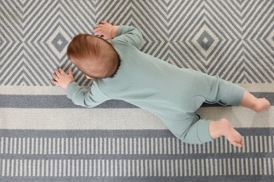 Photo of Cute baby crawling on floor, top view