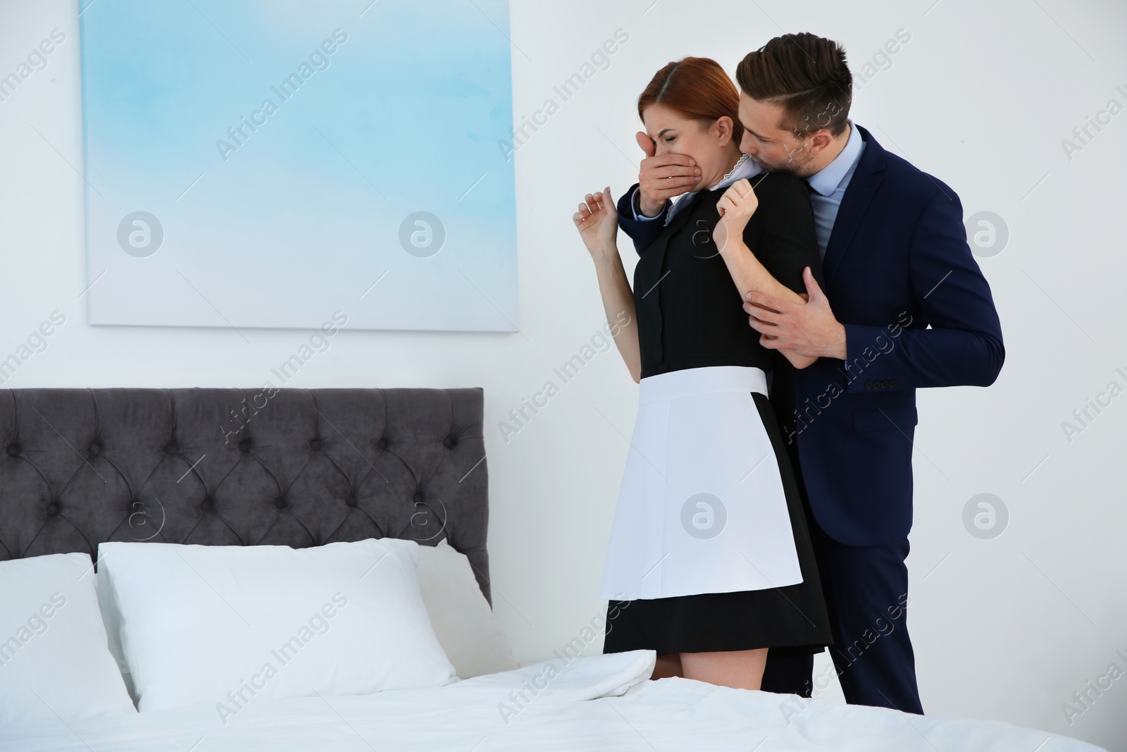 Photo of Man molesting chambermaid in bedroom. Sexual harassment at work