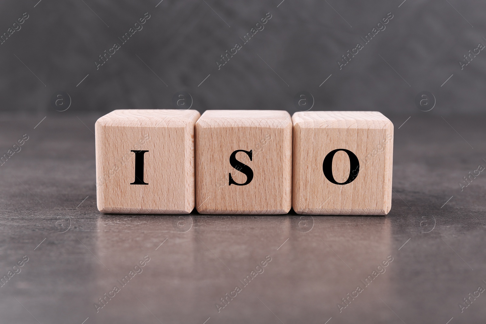 Photo of Wooden cubes with abbreviation ISO on grey textured table