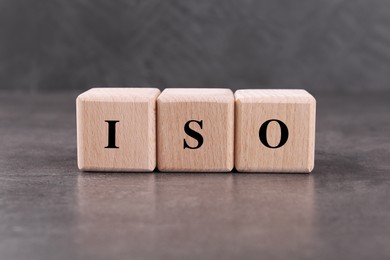 Photo of Wooden cubes with abbreviation ISO on grey textured table