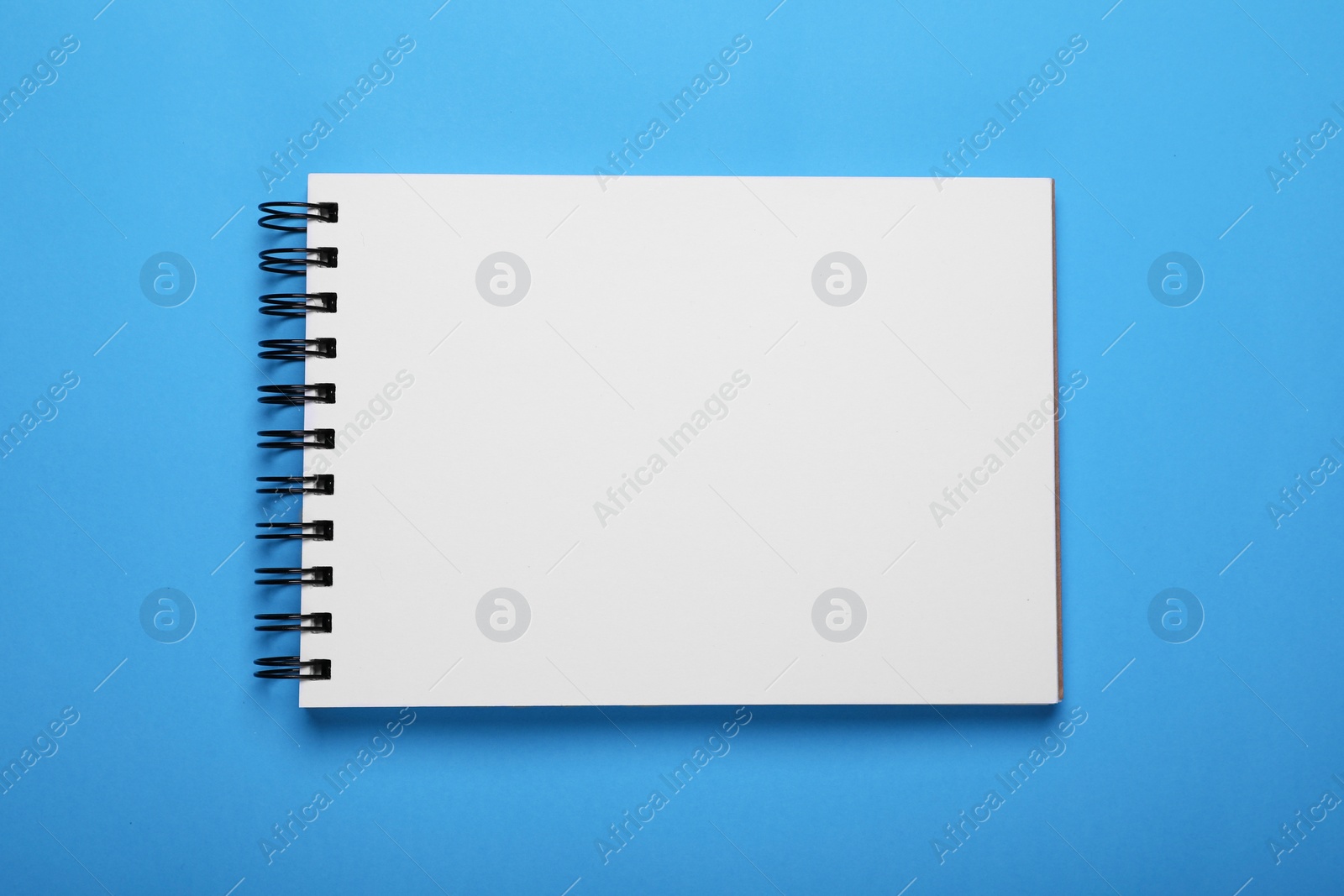 Photo of Open notebook on light blue background, top view