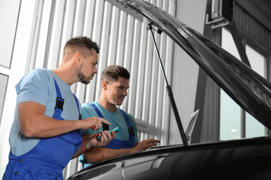 Photo of Mechanics with laptop doing car diagnostic at automobile repair shop