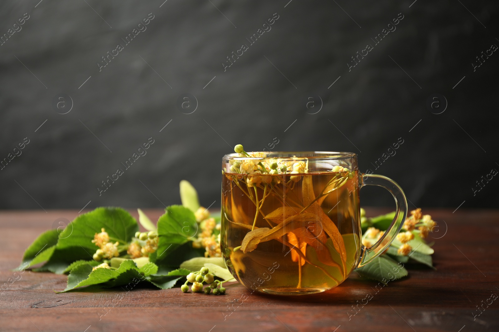 Photo of Cup of tea and linden blossom on wooden table. Space for text
