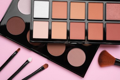 Photo of Different contouring palettes and brushes on pink background, flat lay. Professional cosmetic product