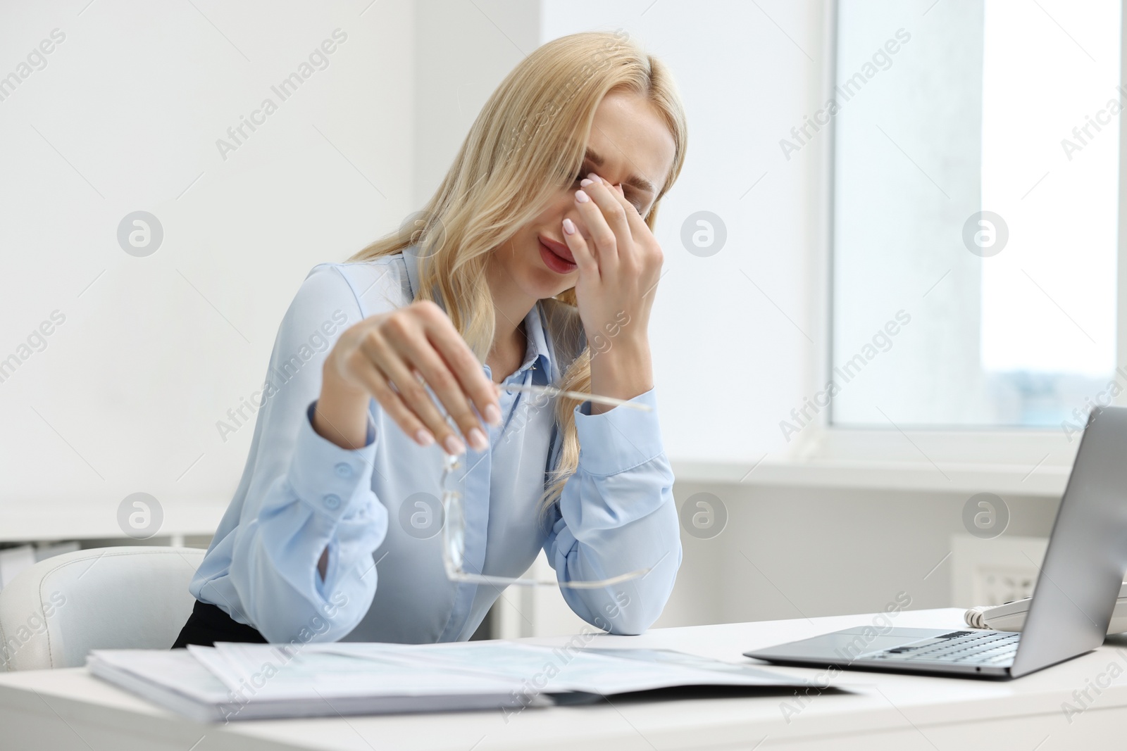 Photo of Overwhelmed woman with glasses at table in office