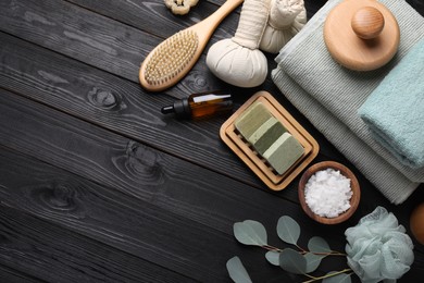 Photo of Flat lay composition with different spa products and eucalyptus branches on black wooden table. Space for text