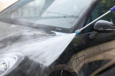 Photo of Washing auto with high pressure water jet at outdoor car wash, closeup