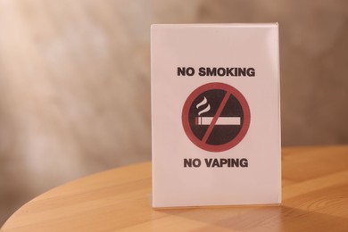 Photo of No Smoking sign on wooden table indoors, space for text
