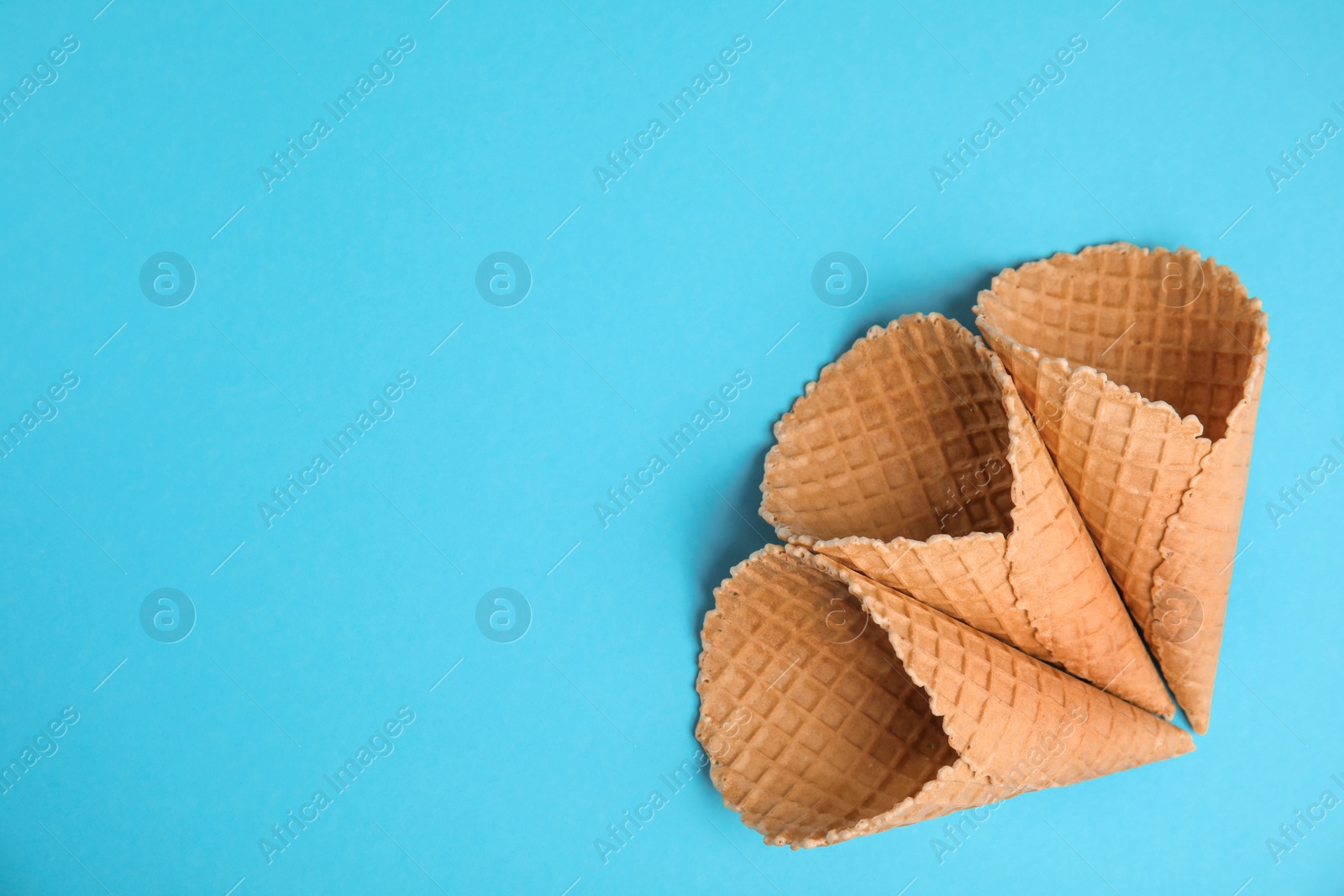 Photo of Waffle empty ice cream cones on color background, flat lay. Space for text