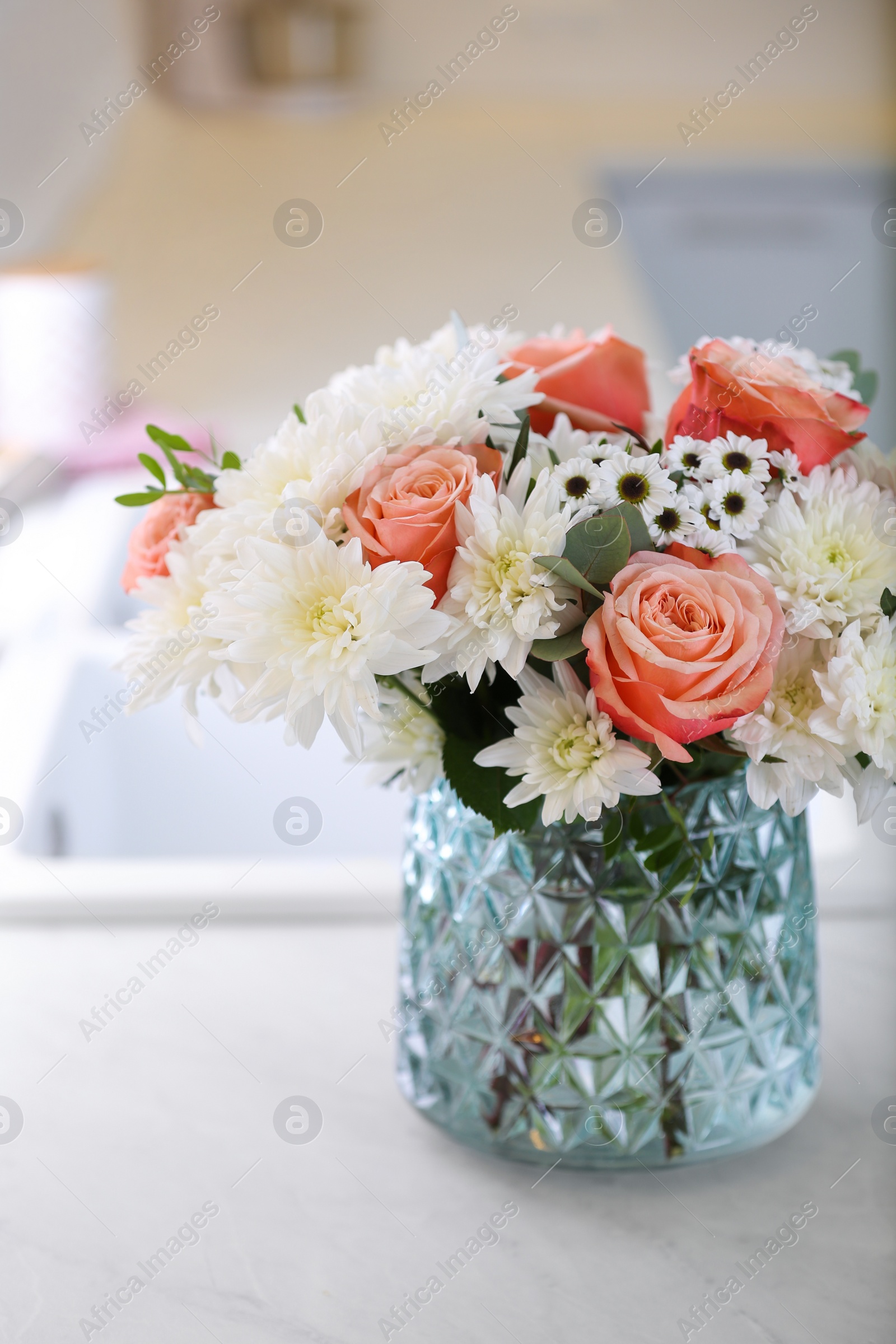 Photo of Vase with beautiful flowers on countertop in kitchen. Interior design