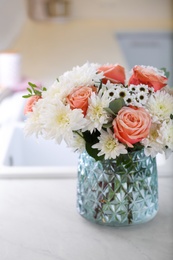 Vase with beautiful flowers on countertop in kitchen. Interior design