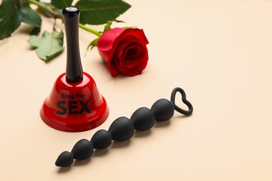 Photo of Bell with text Ring For Sex, anal beads and rose on beige background