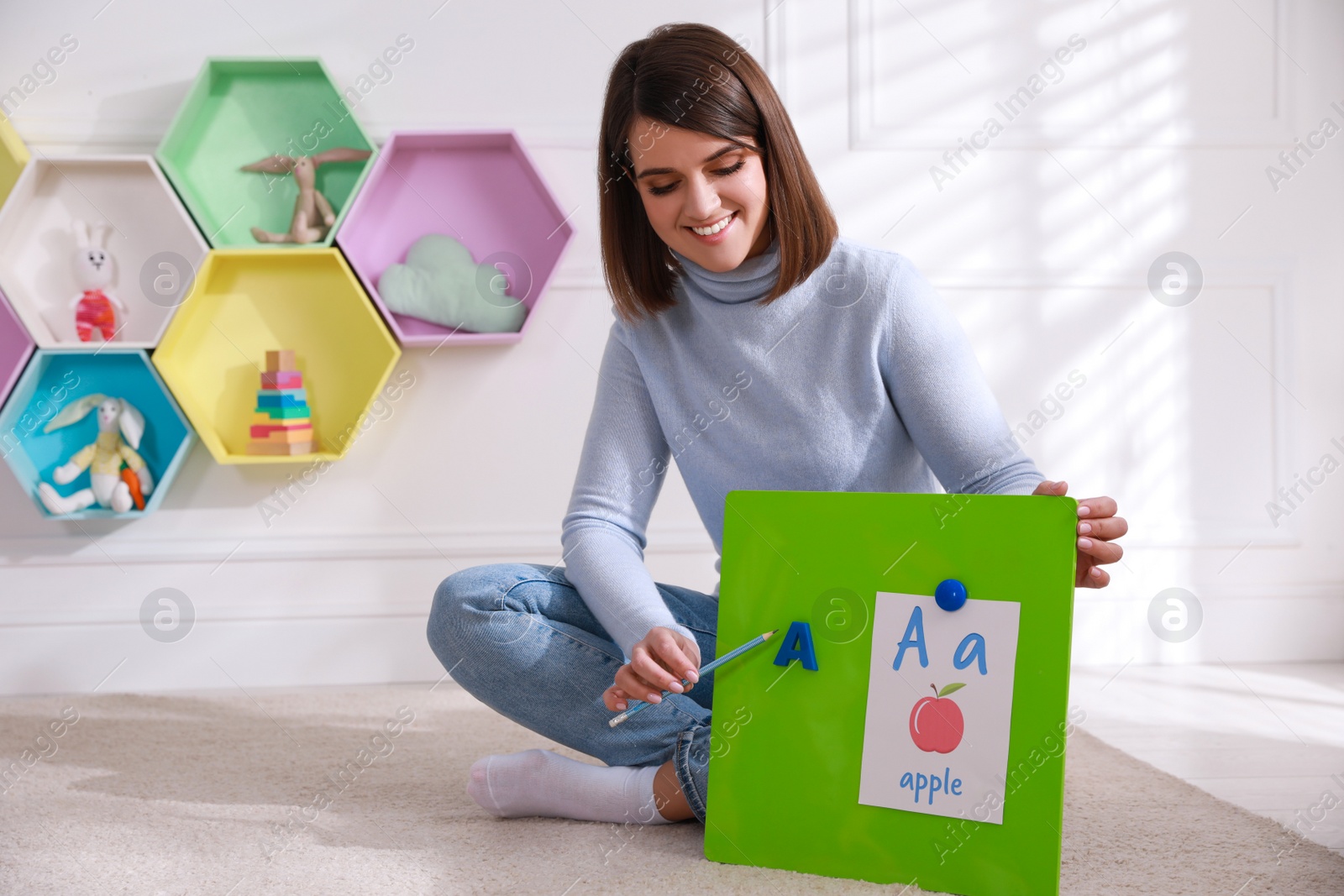 Photo of Happy female English teacher giving lesson indoors. Early childhood education