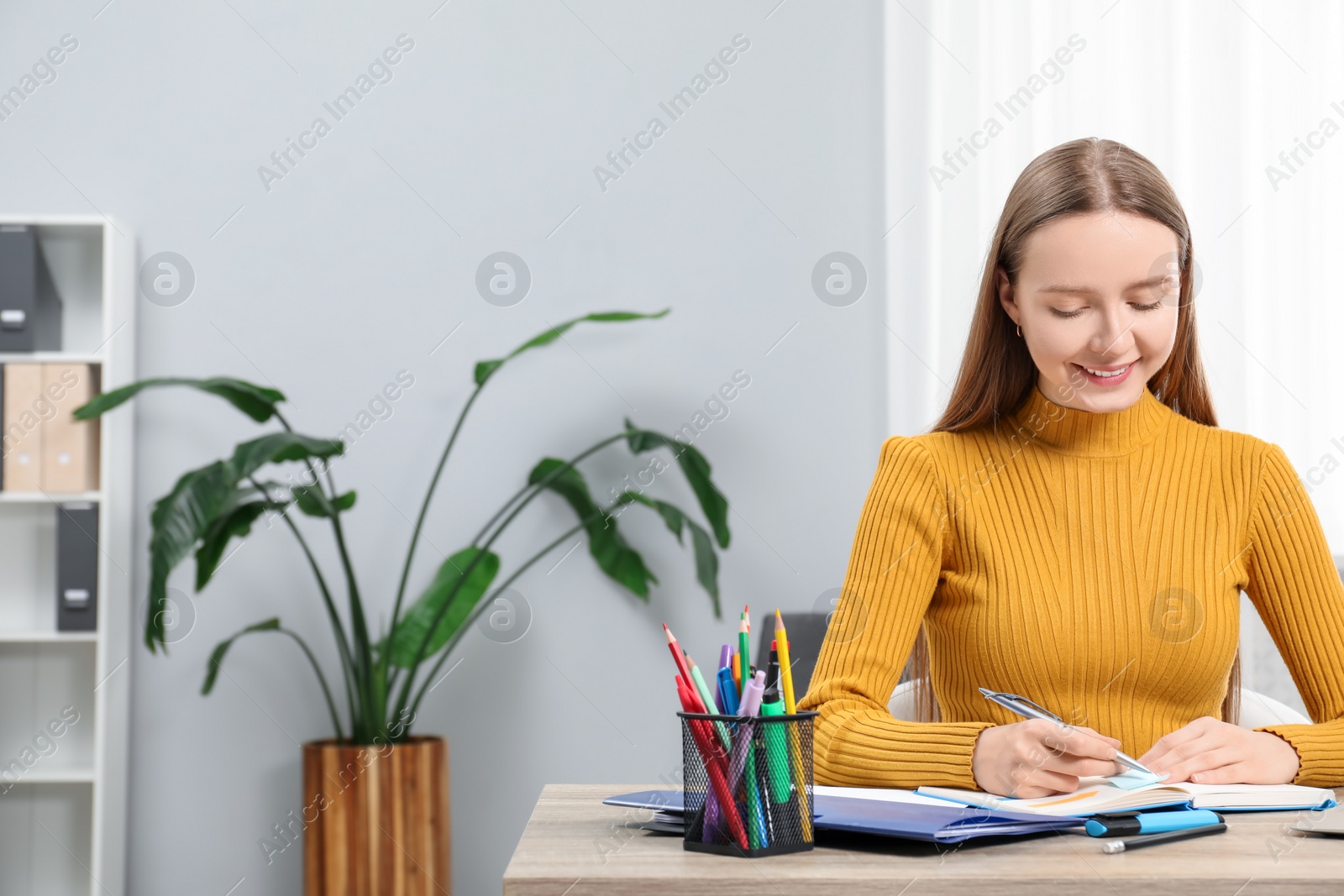 Photo of Woman taking notes at wooden table in office, space for text