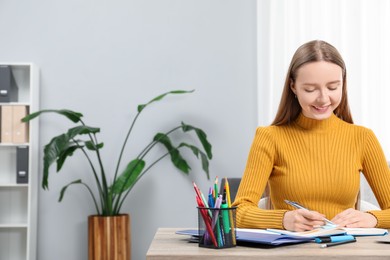 Woman taking notes at wooden table in office, space for text