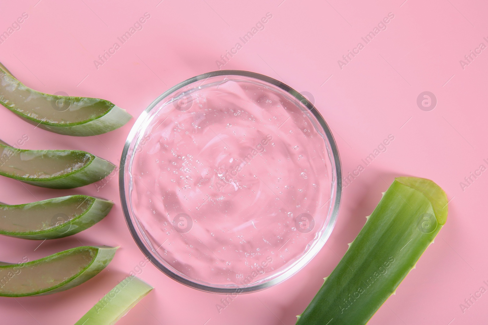 Photo of Aloe vera leaves and cosmetic gel on pink background, top view