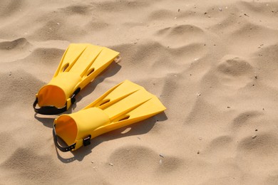 Photo of Pair of yellow flippers on sand. Space for text