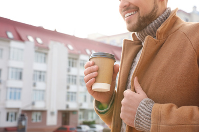 Photo of Man with cup of coffee on city street in morning, closeup