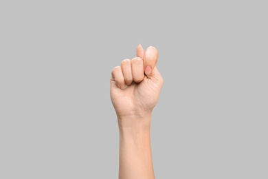 Photo of Woman showing T letter on grey background, closeup. Sign language