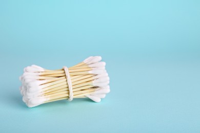 Photo of Bunch of wooden cotton buds on light blue background. Space for text