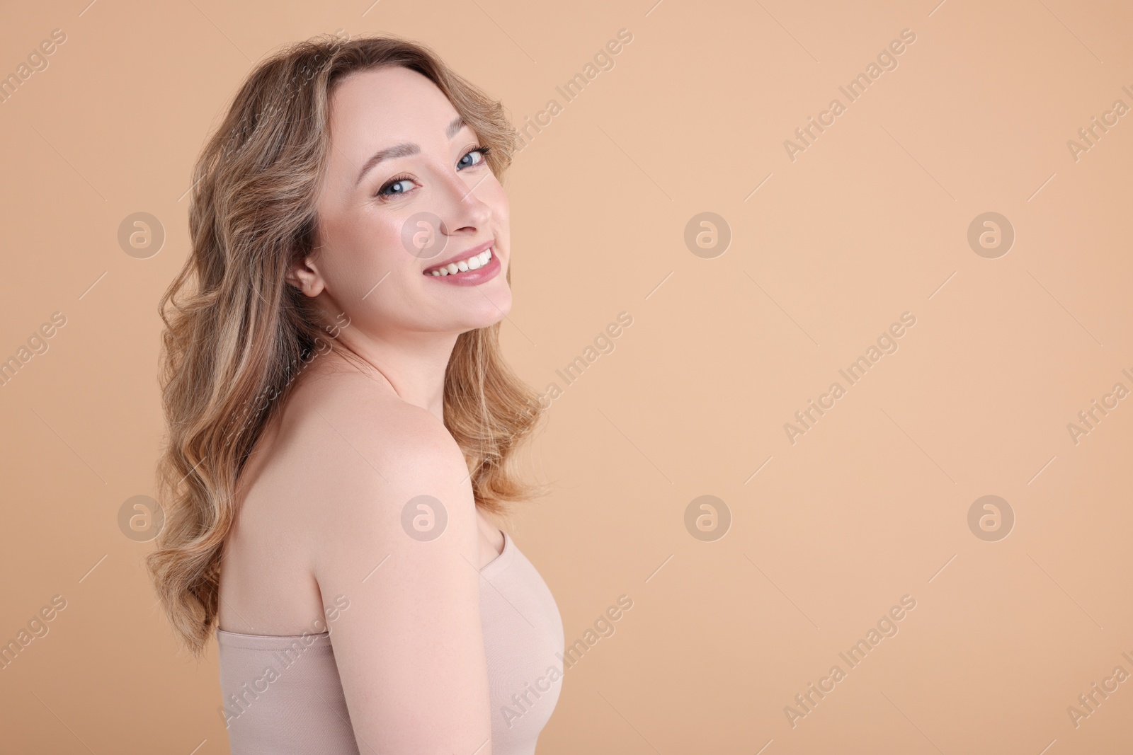 Photo of Portrait of smiling woman on beige background. Space for text